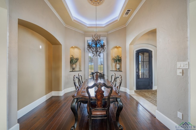 dining room featuring a raised ceiling, crown molding, dark hardwood / wood-style floors, and an inviting chandelier