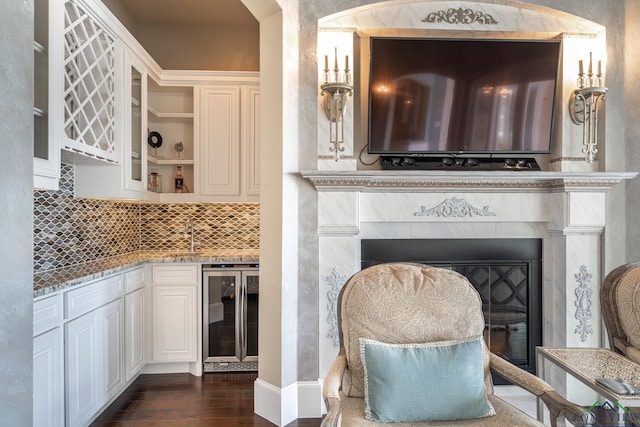 kitchen featuring light stone countertops, white cabinetry, beverage cooler, and dark wood-type flooring