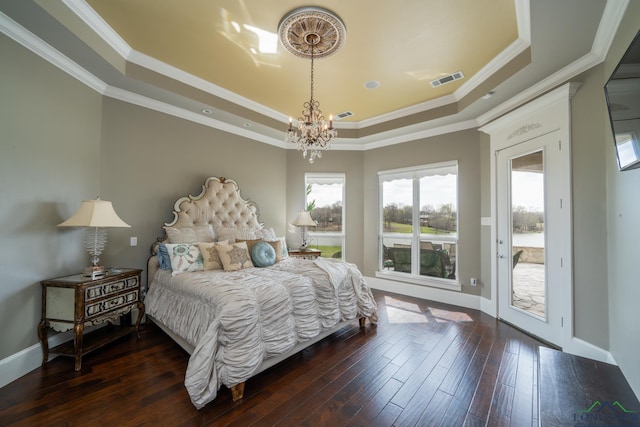 bedroom with access to exterior, dark wood-type flooring, a raised ceiling, a notable chandelier, and crown molding