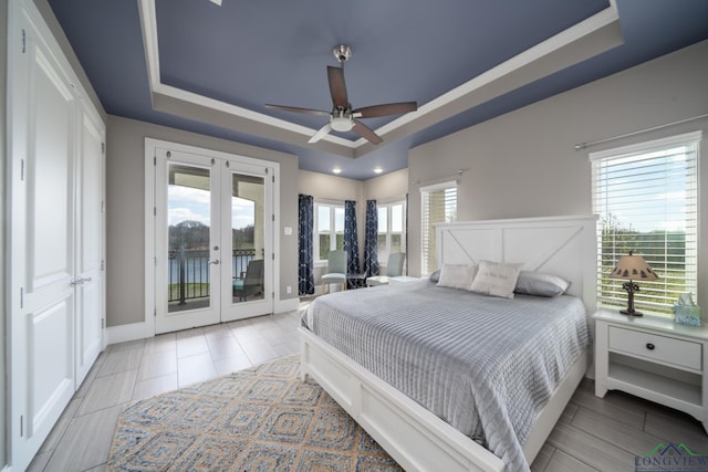 bedroom with ceiling fan, french doors, access to outside, and a tray ceiling