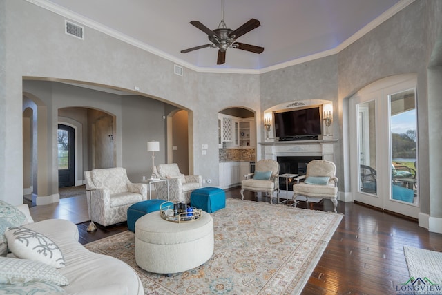 living room featuring ceiling fan, a towering ceiling, dark wood-type flooring, and ornamental molding