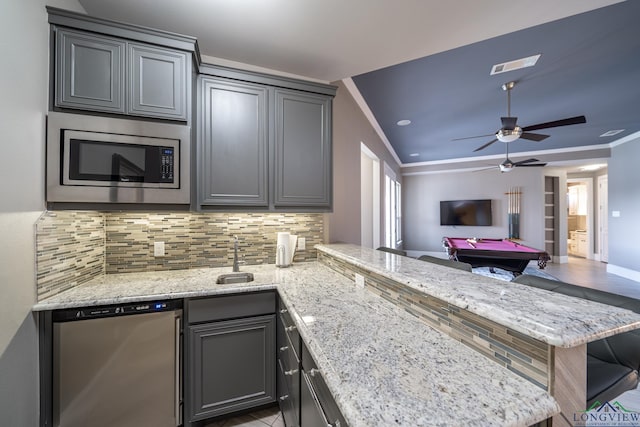 kitchen featuring light stone countertops, stainless steel appliances, billiards, backsplash, and kitchen peninsula