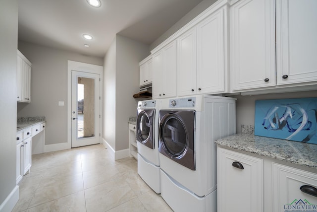 laundry area featuring washer and dryer, cabinets, and light tile patterned flooring