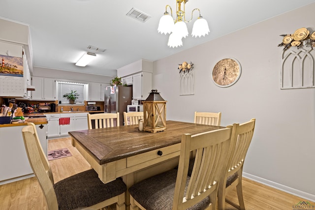 dining space with sink, a chandelier, and light hardwood / wood-style flooring