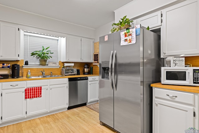 kitchen with white cabinetry, sink, stainless steel appliances, and light hardwood / wood-style floors