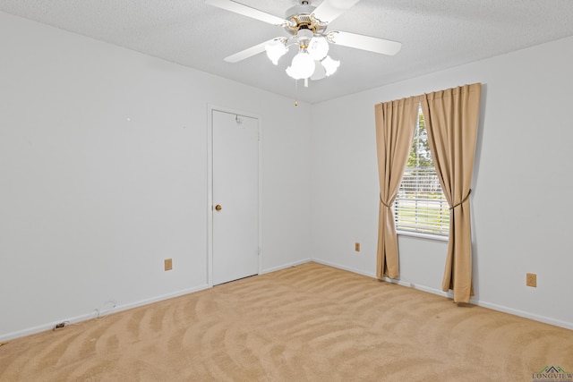 empty room with baseboards, a textured ceiling, light colored carpet, and ceiling fan