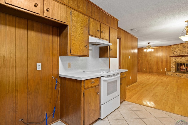 kitchen with brown cabinets, open floor plan, ceiling fan, electric range, and under cabinet range hood
