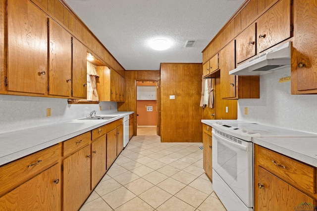 kitchen featuring a textured ceiling, a sink, white appliances, light countertops, and under cabinet range hood
