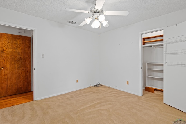 unfurnished bedroom with a spacious closet, visible vents, carpet, and a textured ceiling