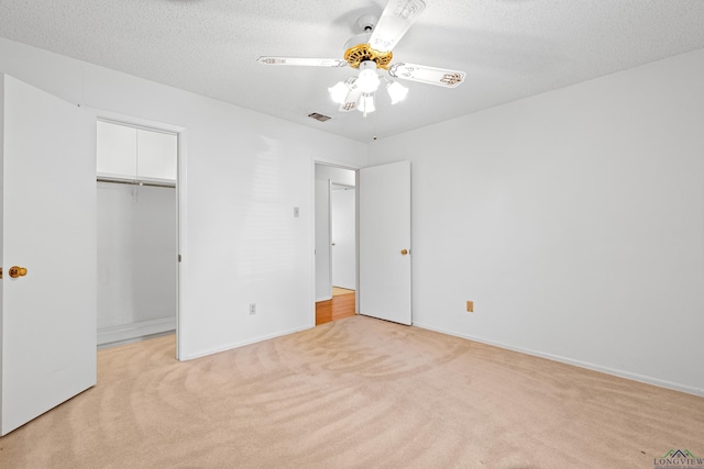 unfurnished bedroom featuring baseboards, visible vents, light colored carpet, a closet, and ceiling fan