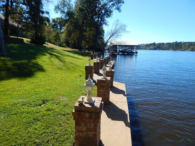 view of dock with a lawn and a water view