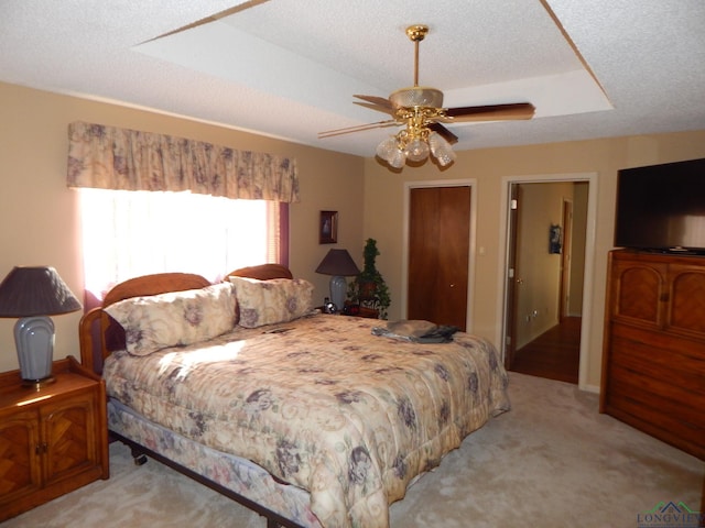 bedroom with ceiling fan, light colored carpet, and a textured ceiling