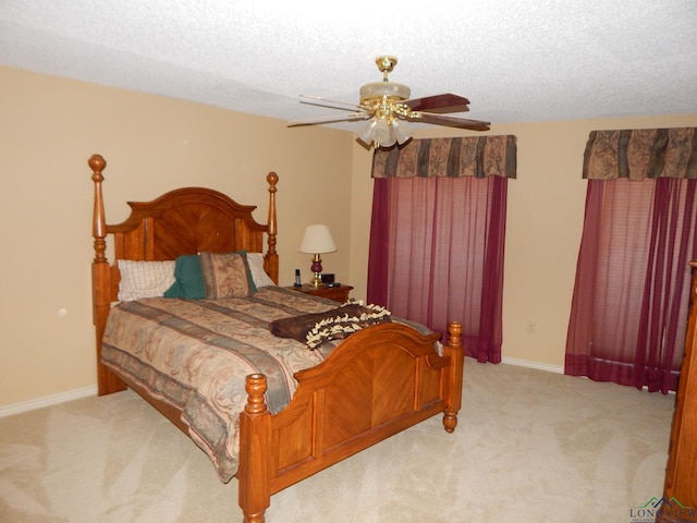 bedroom featuring a textured ceiling, light colored carpet, and ceiling fan