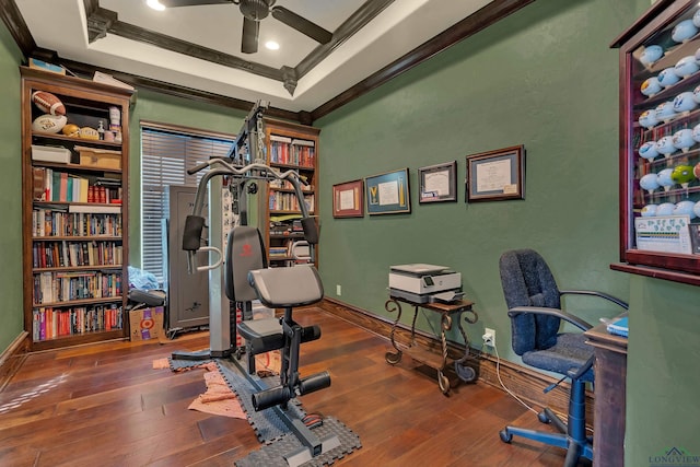 exercise room with dark wood-type flooring, crown molding, and baseboards