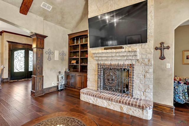 unfurnished living room with baseboards, visible vents, arched walkways, a fireplace with raised hearth, and dark wood-type flooring