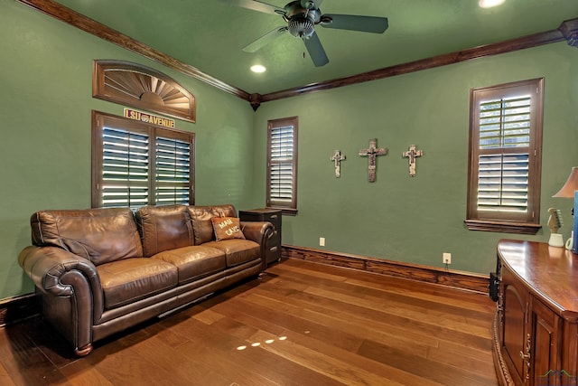 living area with a ceiling fan, crown molding, baseboards, and wood finished floors