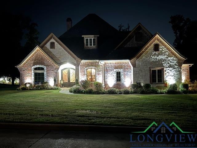 french provincial home featuring stone siding and a yard