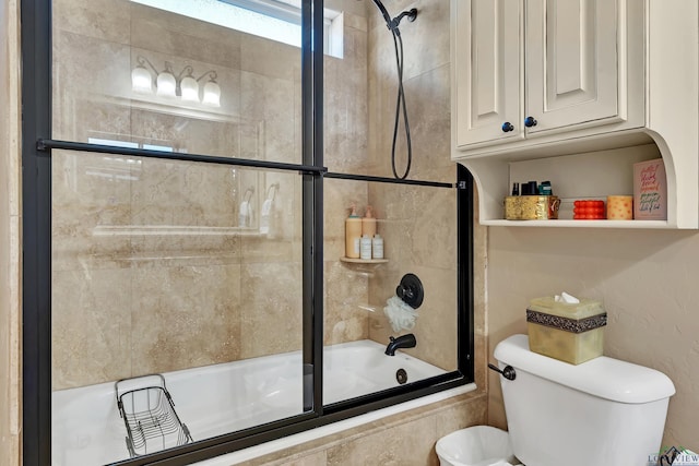 bathroom featuring toilet and bath / shower combo with glass door