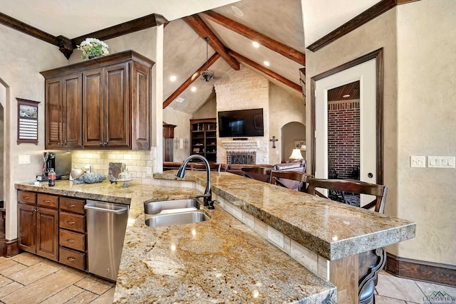 kitchen with light stone counters, a sink, beam ceiling, a kitchen bar, and stainless steel dishwasher