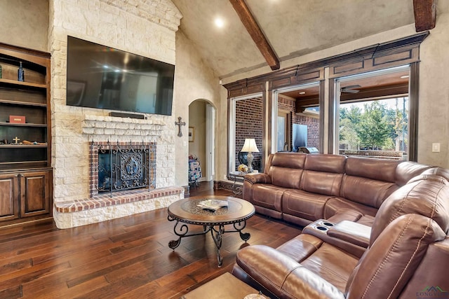 living room featuring built in features, arched walkways, beam ceiling, dark wood finished floors, and a fireplace