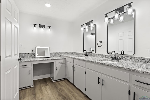 bathroom with hardwood / wood-style floors, vanity, and a textured ceiling