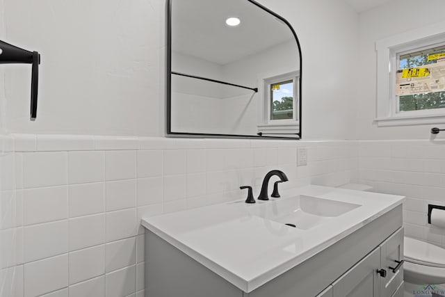 bathroom featuring vanity, toilet, and tile walls