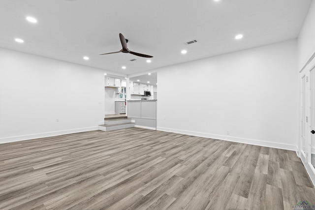 unfurnished living room featuring ceiling fan and light hardwood / wood-style flooring