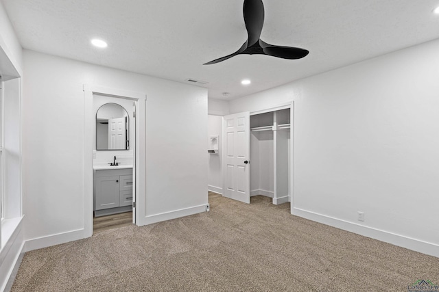 unfurnished bedroom with ceiling fan, a closet, light colored carpet, and ensuite bath