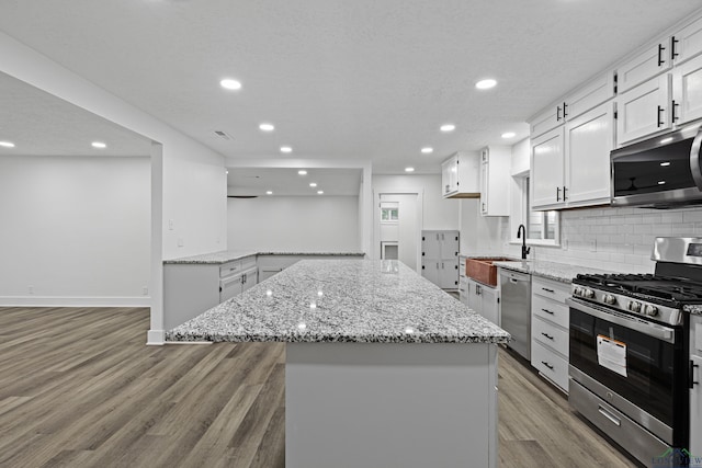 kitchen featuring light stone counters, white cabinets, stainless steel appliances, and a kitchen island