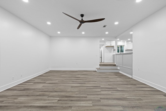 unfurnished living room featuring wood-type flooring, ceiling fan, and sink