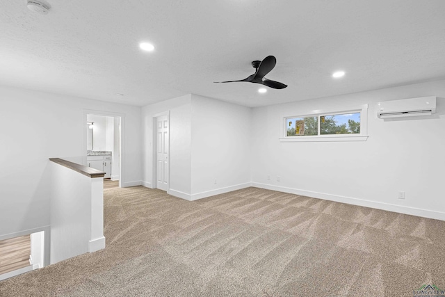 unfurnished living room with ceiling fan, light colored carpet, a textured ceiling, and a wall unit AC