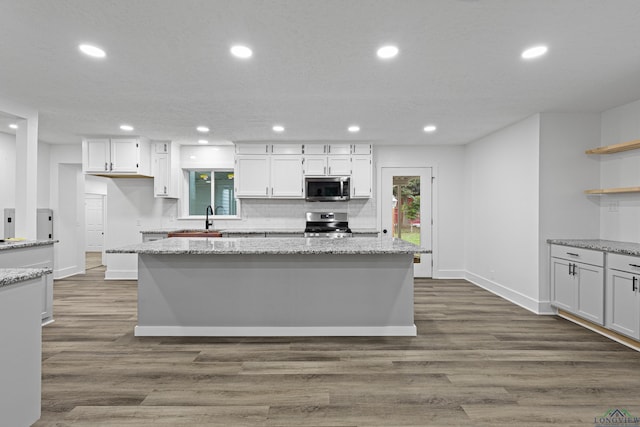 kitchen featuring white cabinets, appliances with stainless steel finishes, dark hardwood / wood-style flooring, and a kitchen island