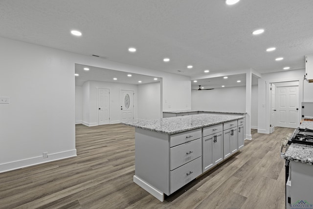 kitchen featuring ceiling fan, light stone countertops, and white cabinetry