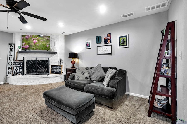 carpeted living area featuring a brick fireplace, baseboards, visible vents, and a ceiling fan