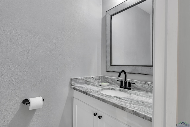 bathroom featuring a textured wall and vanity