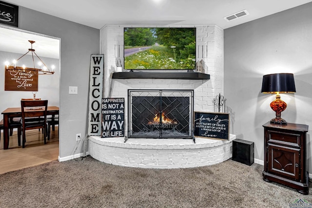 room details with baseboards, visible vents, an inviting chandelier, carpet floors, and a brick fireplace