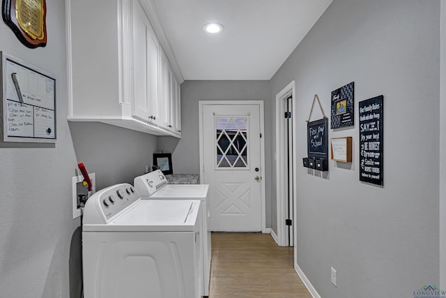 laundry room with baseboards, light wood finished floors, cabinet space, and washer and dryer