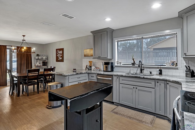 kitchen featuring stainless steel appliances, visible vents, light wood-style flooring, gray cabinetry, and a sink