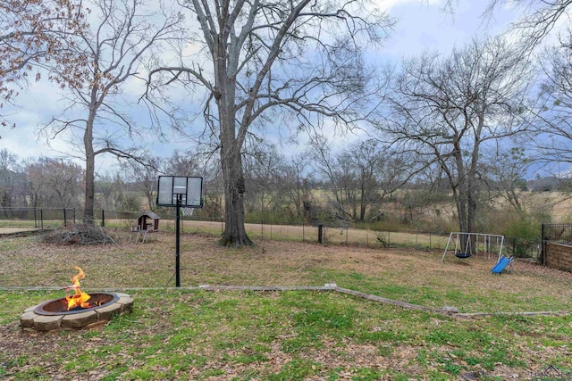 view of yard featuring fence, a fire pit, and a playground