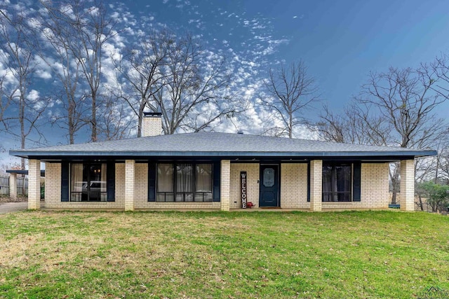 view of front of house featuring a front yard, brick siding, and a chimney