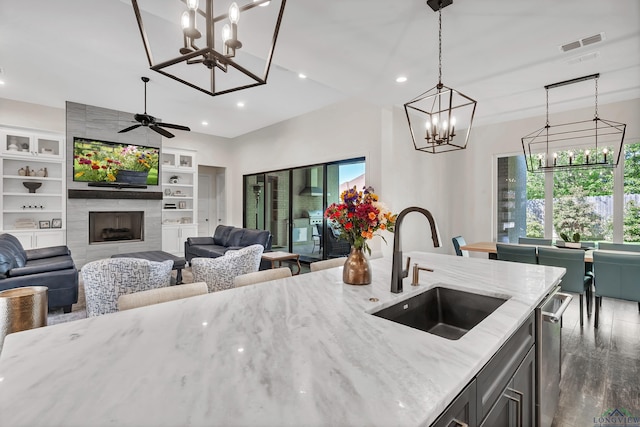kitchen with light stone counters, a sink, pendant lighting, dark wood finished floors, and visible vents