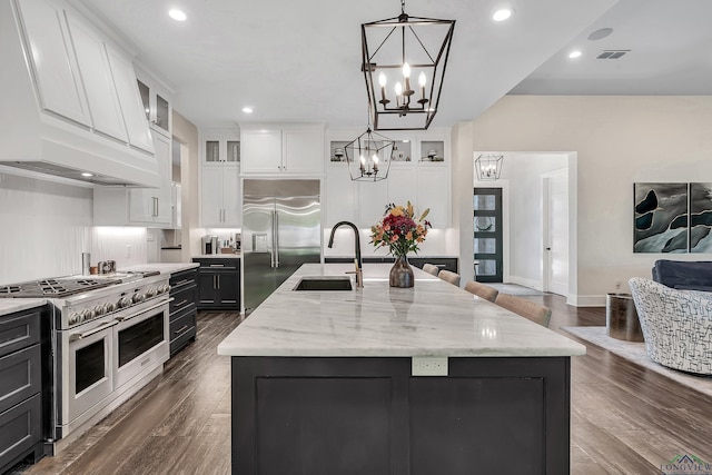kitchen with high quality appliances, a sink, white cabinets, a notable chandelier, and visible vents