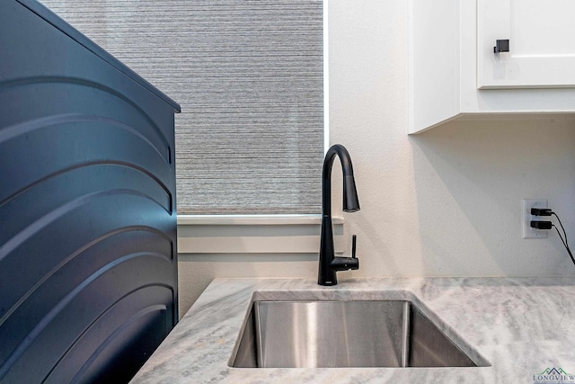 interior details featuring white cabinets, a sink, and light countertops