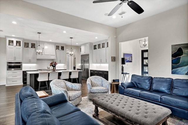 living room with recessed lighting, visible vents, dark wood-style floors, and ceiling fan with notable chandelier