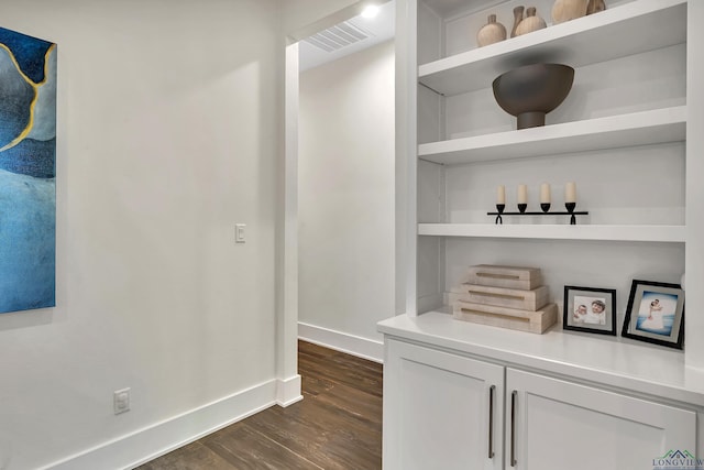 corridor with dark wood-type flooring, visible vents, and baseboards