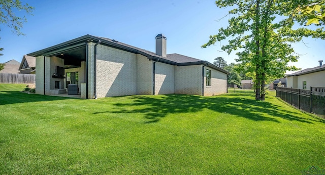 rear view of property with fence, a chimney, brick siding, and a yard