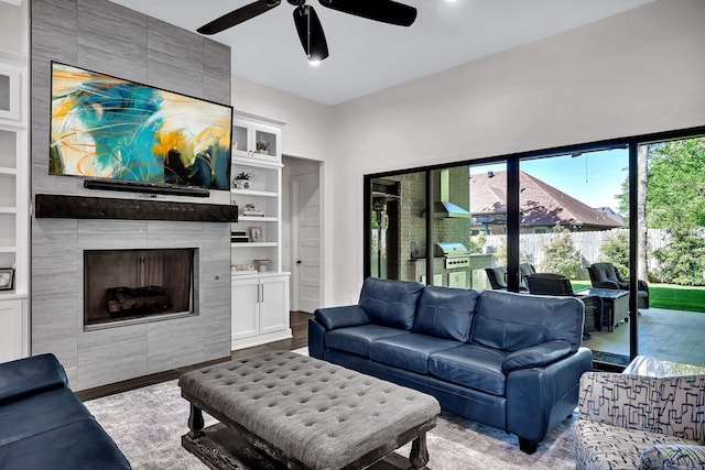 living room featuring a ceiling fan, wood finished floors, built in shelves, a tiled fireplace, and recessed lighting