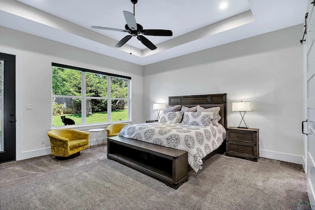 carpeted bedroom with ceiling fan, baseboards, and a raised ceiling