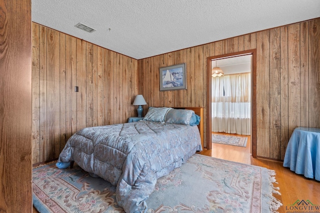 6940 Fm 778, Hawkins, TX 75765 - bedroom featuring wooden walls, a textured ceiling, and wood finished floors