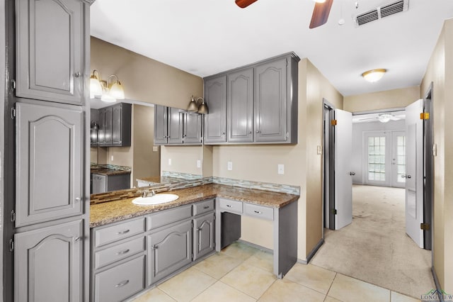 kitchen featuring a sink, light carpet, a ceiling fan, and gray cabinetry